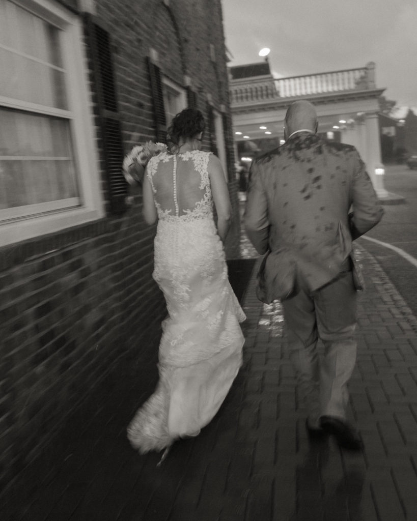 Elegant couple enjoy a sudden cloud burst in front of the Molly Pitcher Inn in Red Bank, NJ by wedding photographer Laura Billingham