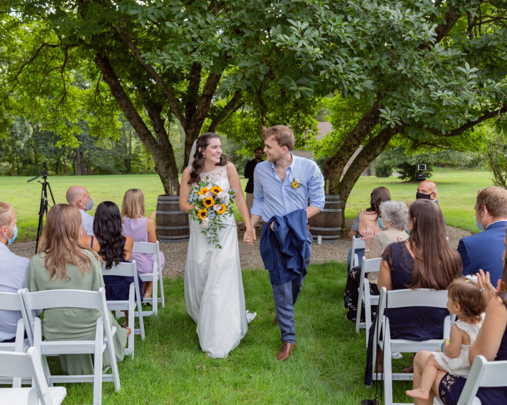 joyful bride and groom exit their rustic chic wedding ceremony at the Woolverton Inn, photographed by Laura Billingham