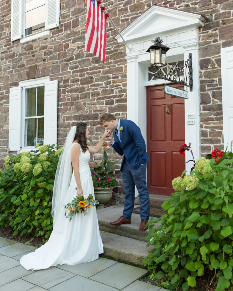 romantic groom kisses the bride's hand at the Woolverton Inn in Stockton, NJ. Wedding photography by Laura Billingham