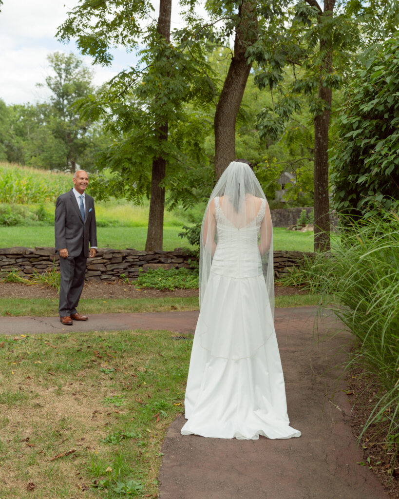 elegant bride walks toward her waiting father for a first look by NJ photographer Laura Billingham