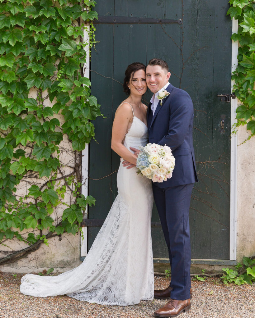 Portrait of an elegant bride and groom in front of a green door by Laura Billingham Photography