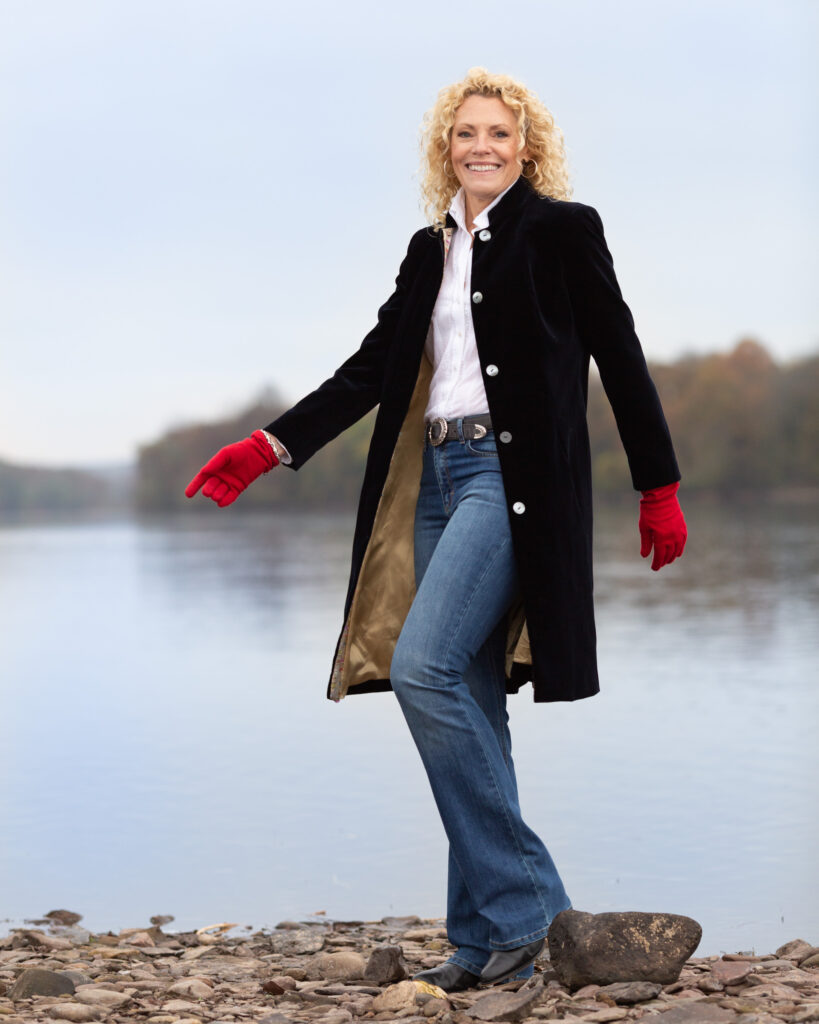 Behind the scenes photograph of Laura Townsend Barnes, author, conservationist, restaurateur and race car driver on the banks of the Delaware River in Frenchtown, NJ photographed on location for River Towns Magazine by Laura Billingham Photography