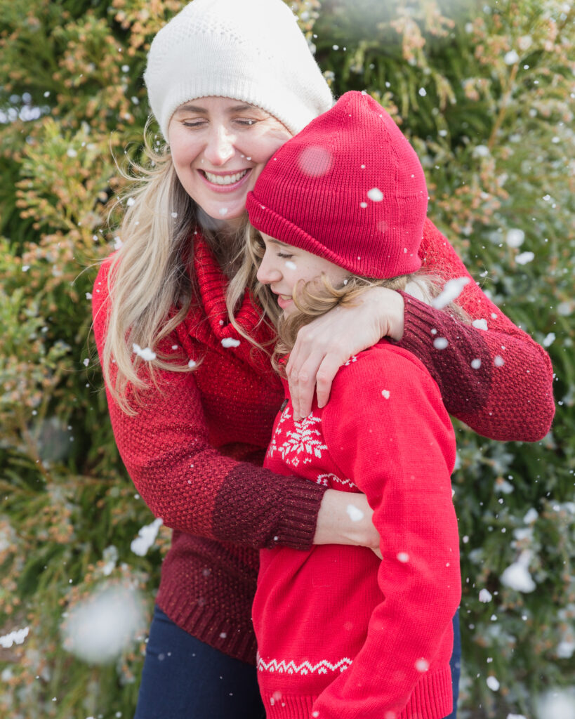 A mom hugs her school age son under snowflakes during a holiday mini session at Black Shed in Stockton, NJ photography by Laura Billingham