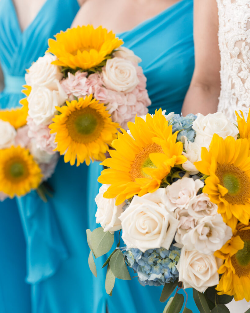 Detail of bridesmaids bouquets with turquoise dresses, yellow sunflowers, white roses, blue hydrangea photo taken in the summer at the Molly Pitcher Inn in Red Bank, NJ by Laura Billingham Photography