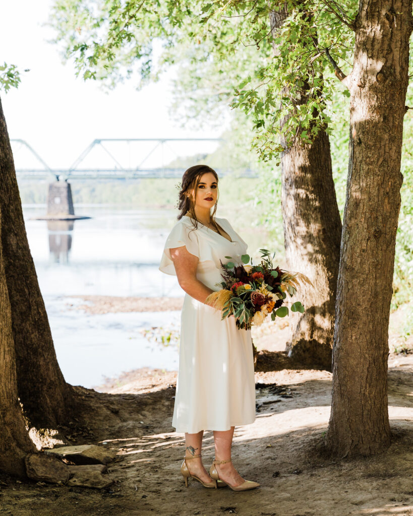 Portrait of a bride by the Delaware River after micro wedding at 15 Landsdowne in Frenchtown, NJ photographed by Laura Billingham