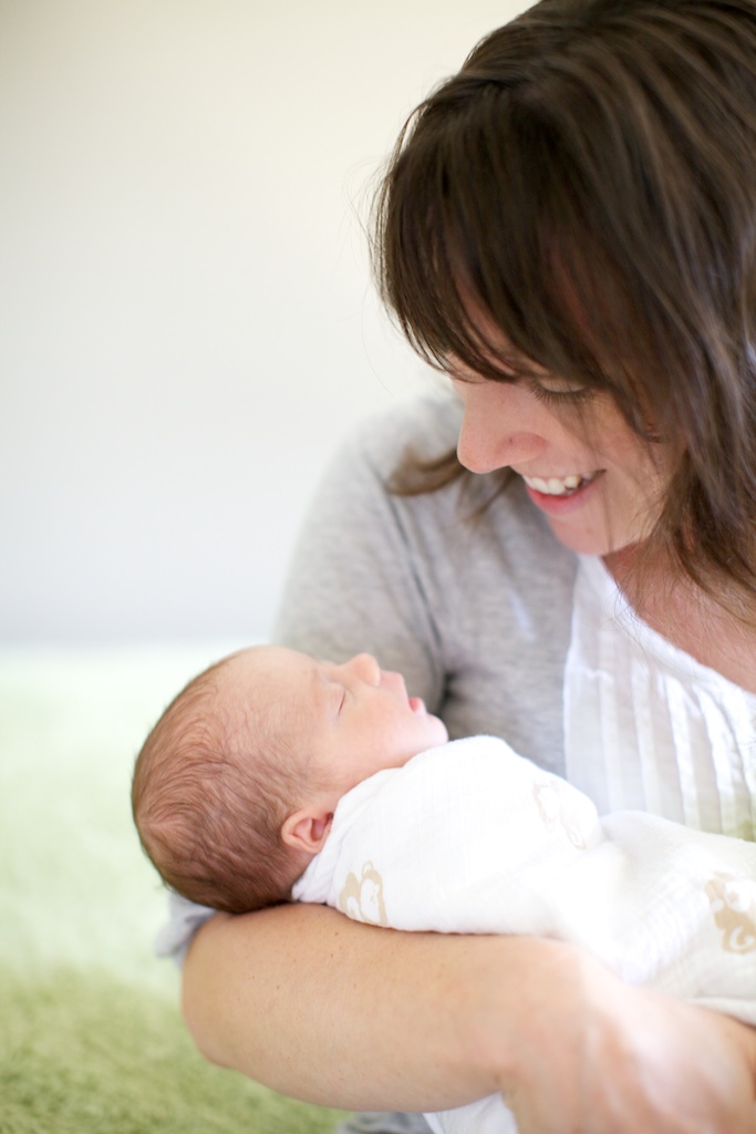 mother smiling at newborn twin baby on the forehead by Laura Billingham Photography