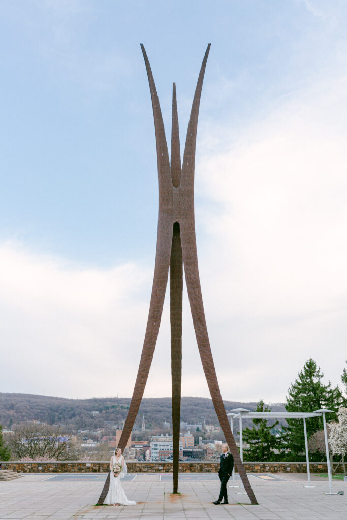 Elegant bride and groom lean at the base of the Symbol of Progress sculpture in Bethlehem, PA by Laura Billingham Photography