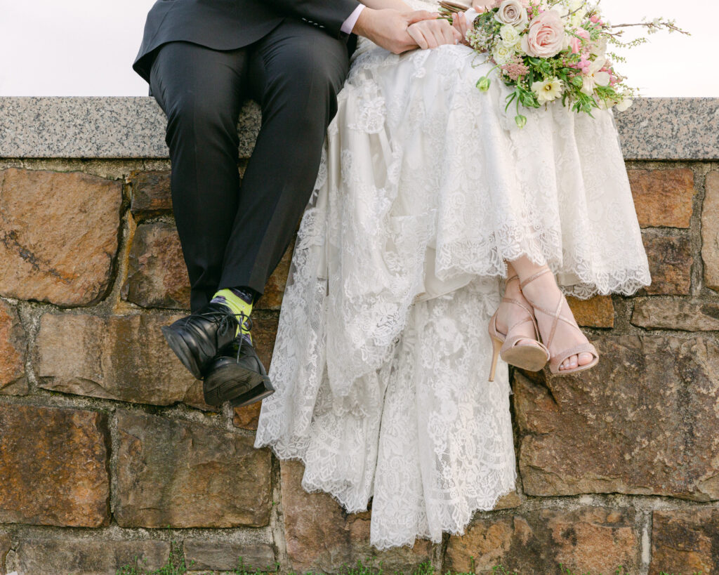 Close up detail of an elegant bride and groom's legs while they sit on a stone wall in the plaza at the Bethlehem Area Public Library