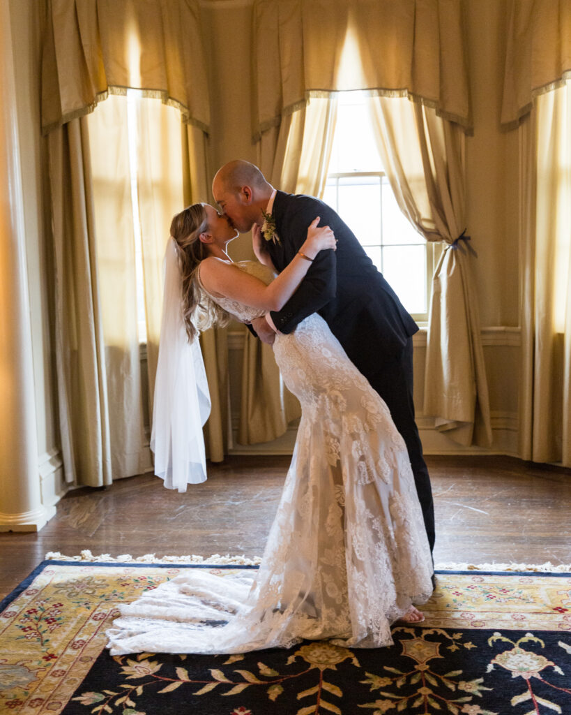 Bride and groom kiss with a dip after saying their vows at the historic Sayre Mansion