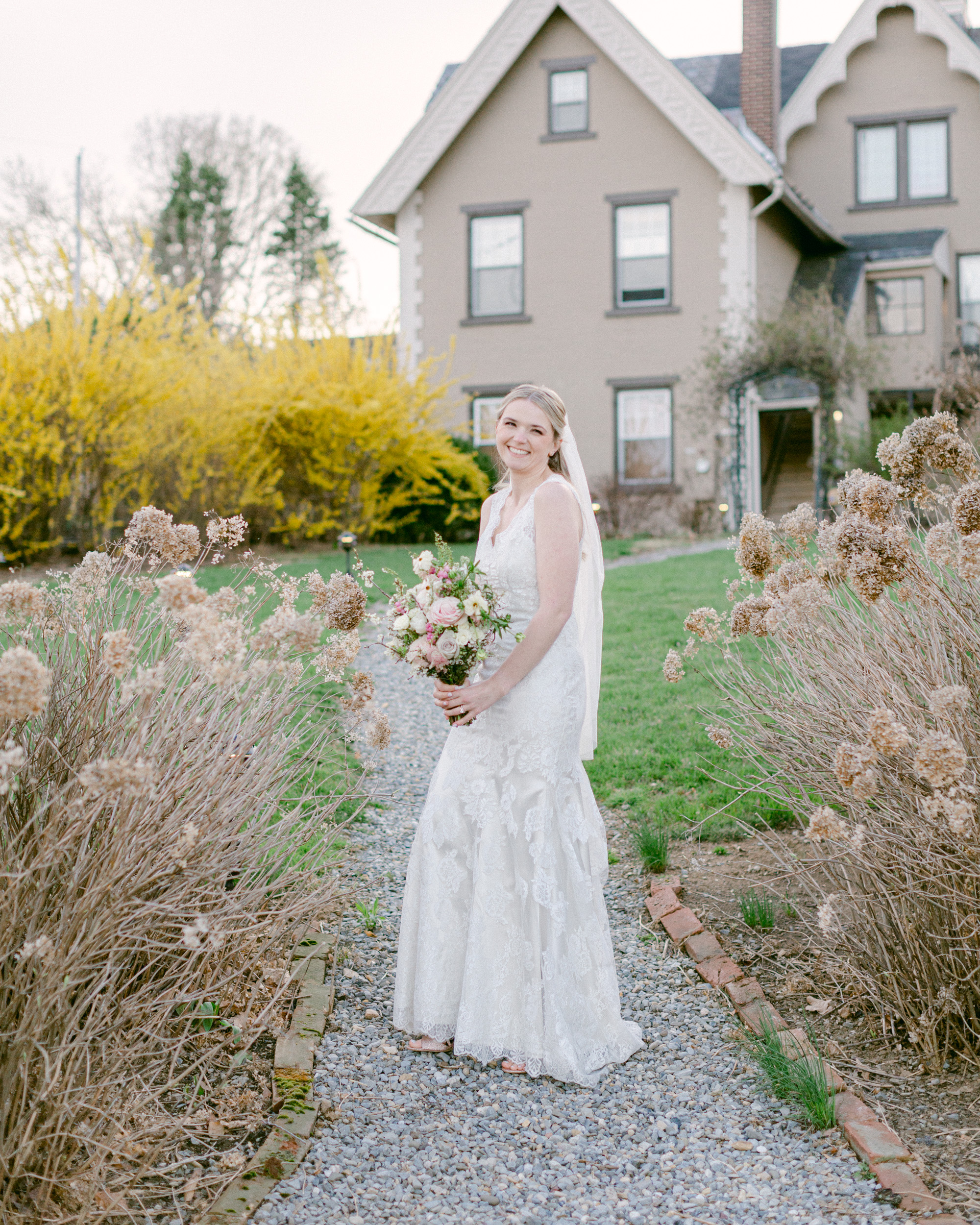 Elegant bride with a luxurious spring bouquet in front of the carriage house at the Sayre Mansion in Bethlehem, PA by Laura Billingham Photography