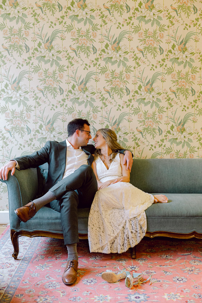 Elegant bride and groom snuggle on a couch at Mountain Lakes House in Princeton, NJ by Laura Billingham Photography