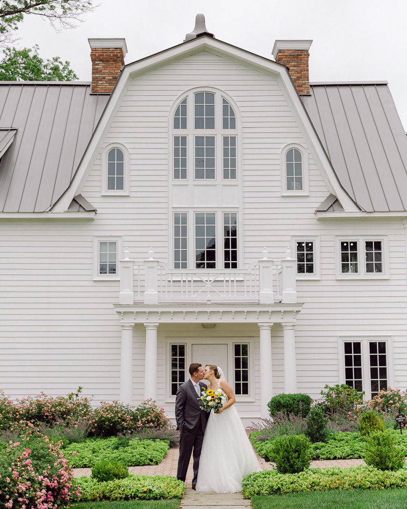 Elegant bride and groom kiss in front of the Coach House at The Ryland Inn in Whitehouse Station, NJ by Laura Billingham Photography