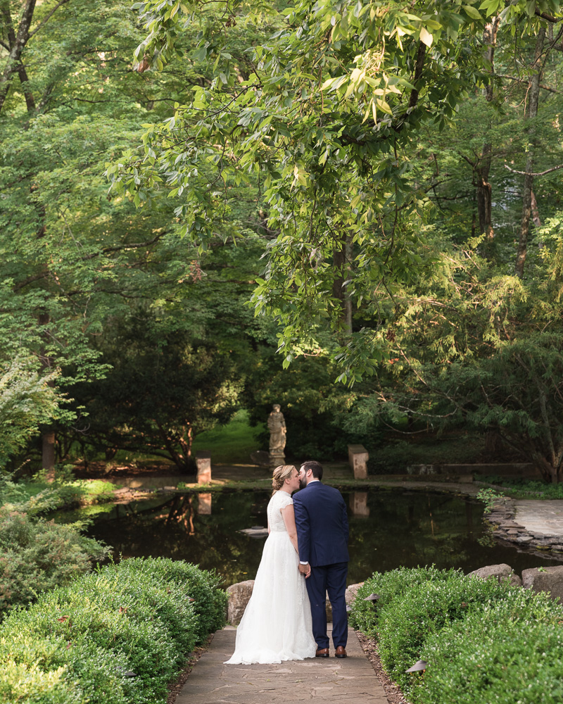 Elegant bride and groom pose in front of pond at HollyHedge Estate in New Hope, PA