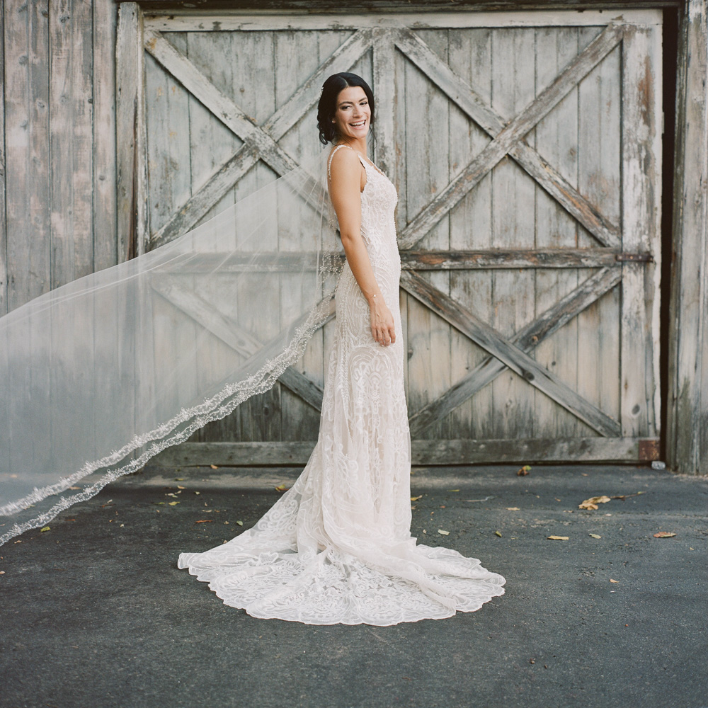 Elegant bride with long veil laughs outside the Bernards Inn in Bernardsville, NJ by film photographer Laura Billingham
