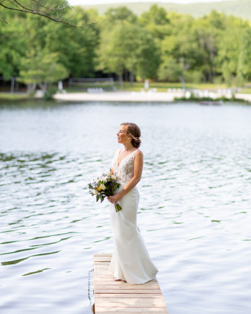 Elegant bride stands in profile on a dock at Mountain Springs Lake Resort