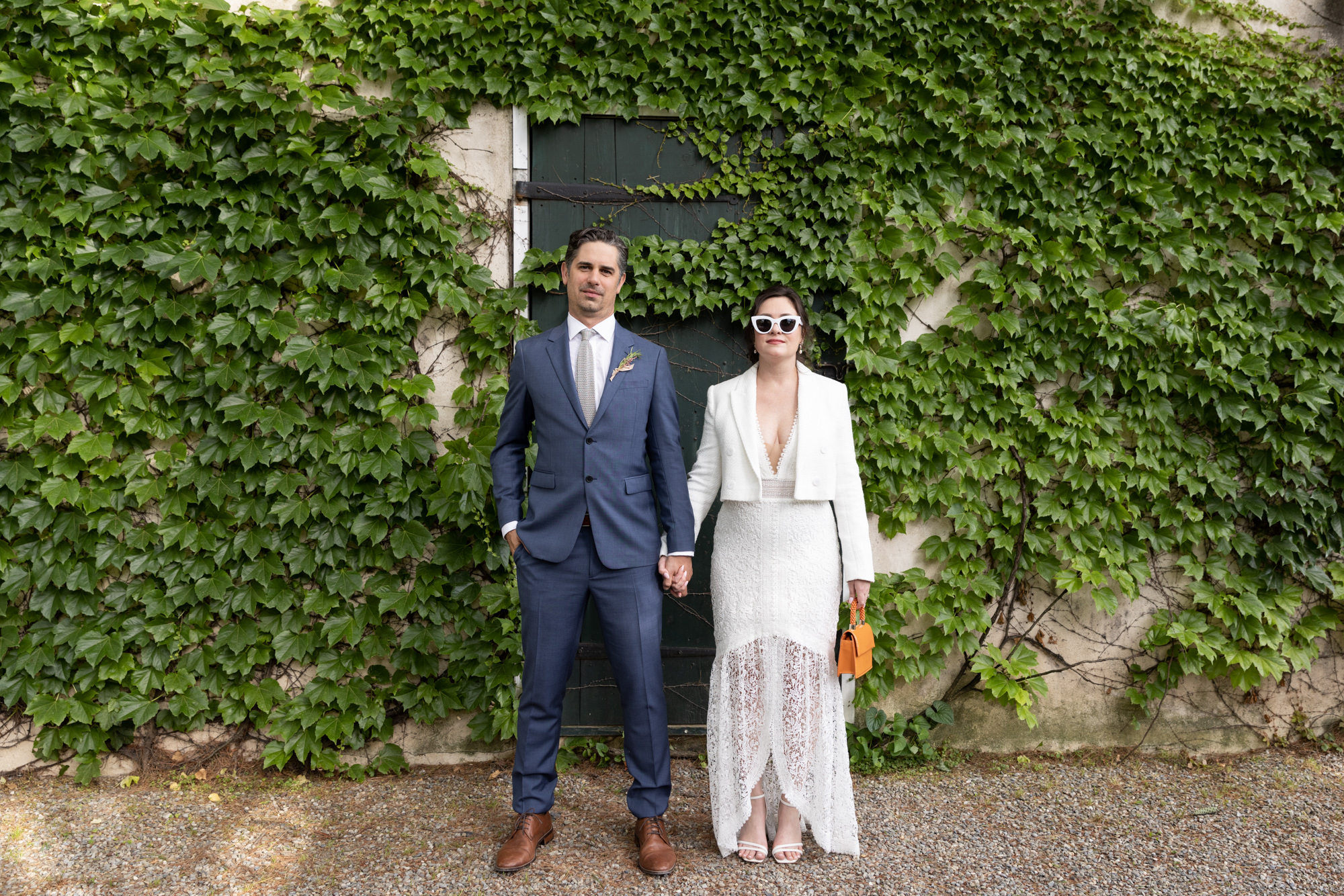 Cool bride and groom pose in front of an ivy covered wall at Bridgeton House on the Delaware in Bucks County, PA