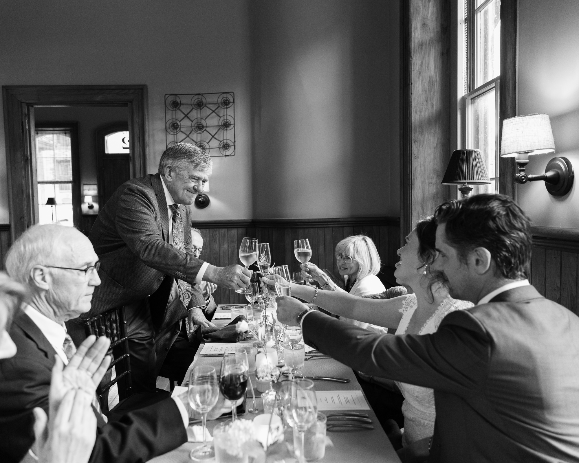 black and white photo of father giving bride and groom a wedding toast at Canal House Station in Milford, NJ