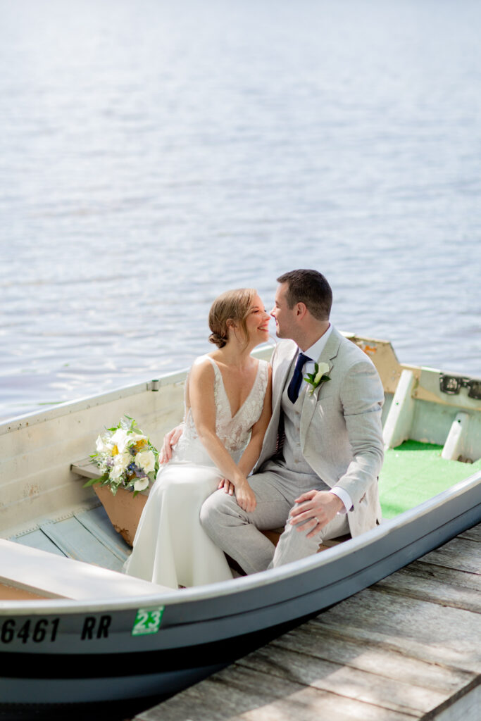 Portrait of an elegant bride and groom sharing a kiss in a rowboat on the lake at Mountain Springs Lake Resort in the Poconos in Reeders, PA