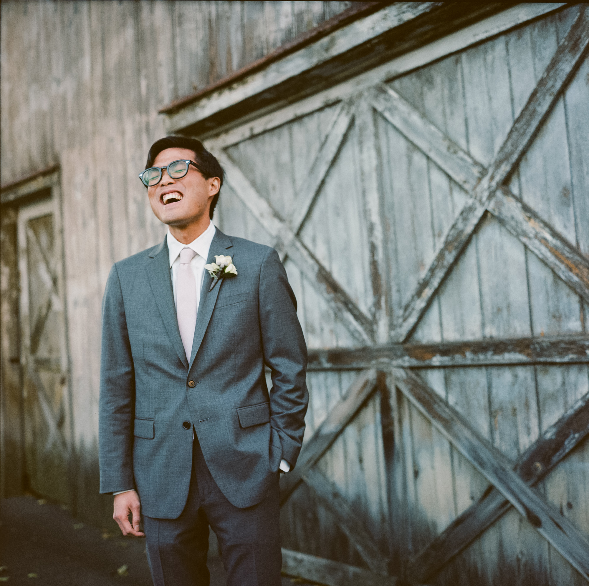 Groom in an elegant gray suit laughs before his wedding at the Bernards Inn in Bernardsville, NJ