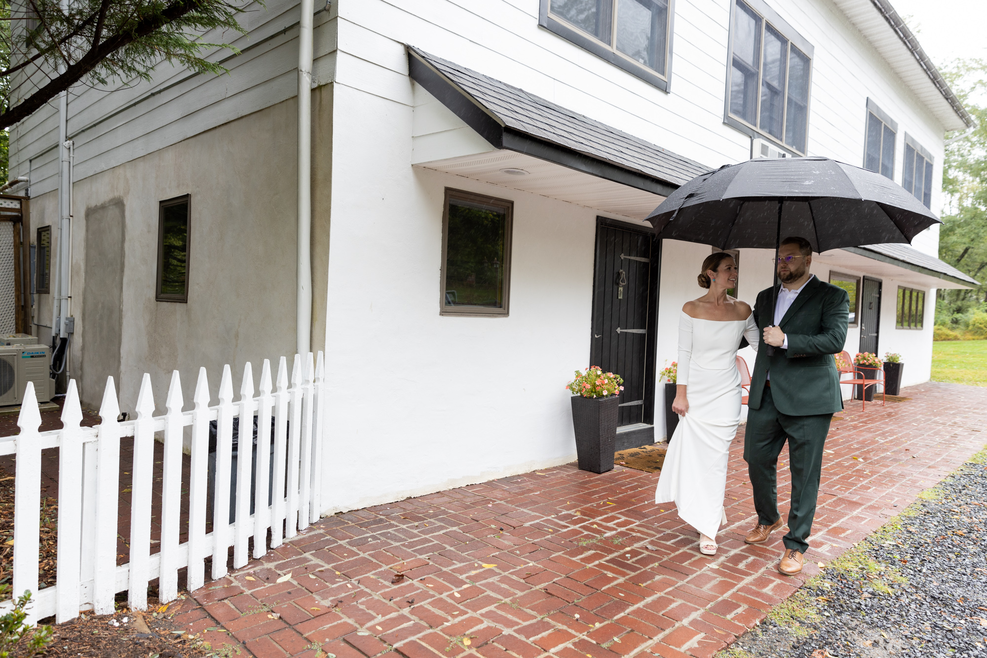 Portrait of an elegant bride and groom walking toward their ceremony while holding an umbrella at their wedding at Chimney Hill Inn Estate in Lambertville, NJ