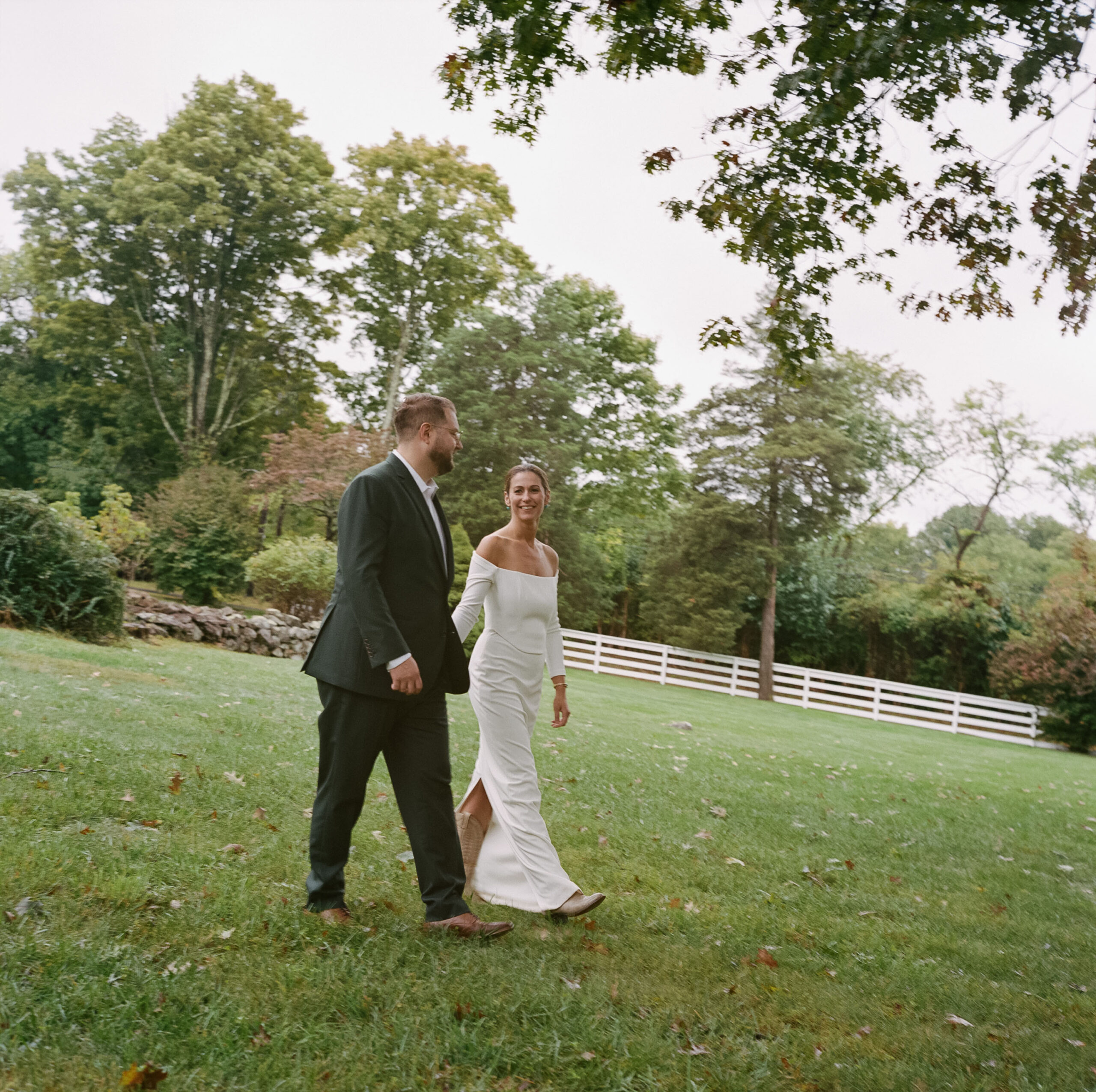 Medium format color film photograph of an elegant bride and groom walk holding hands after their wedding ceremony at Chimney Hill Estate Inn in Lambertville, NJ