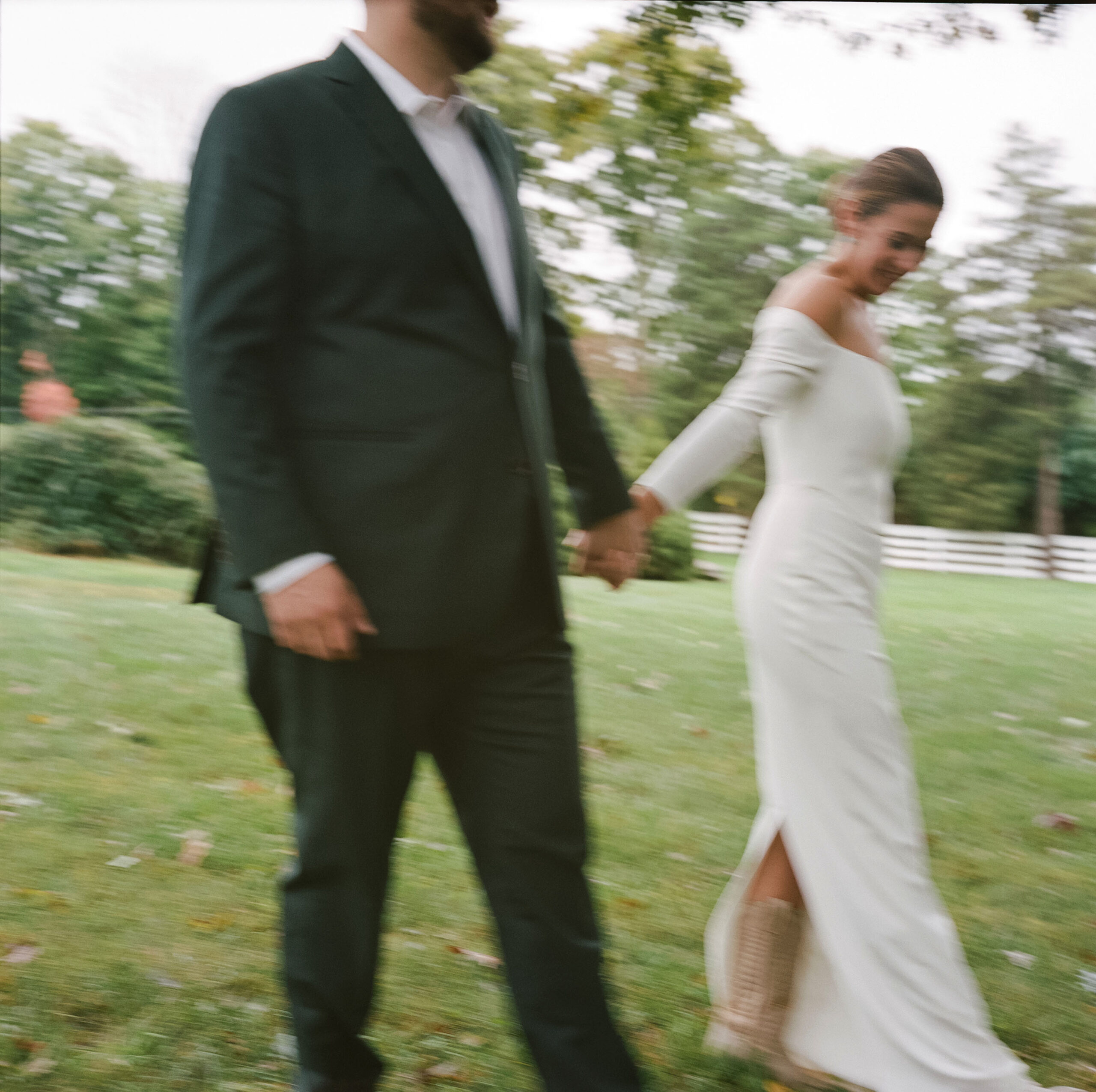 blurry color photo on medium format film of a bride and groom holding hands and walking after their wedding ceremony at Chimney Hill Estate Inn in Lambertville, NJ