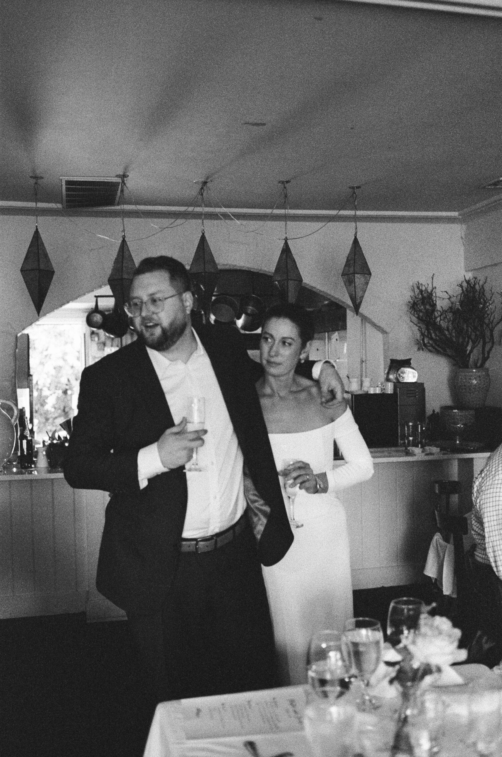 black and white photo on 35mm film of groom with arm around the bride giving an impromptu toast at an intimate wedding reception at Brian's restaurant in Lambertville, NJ