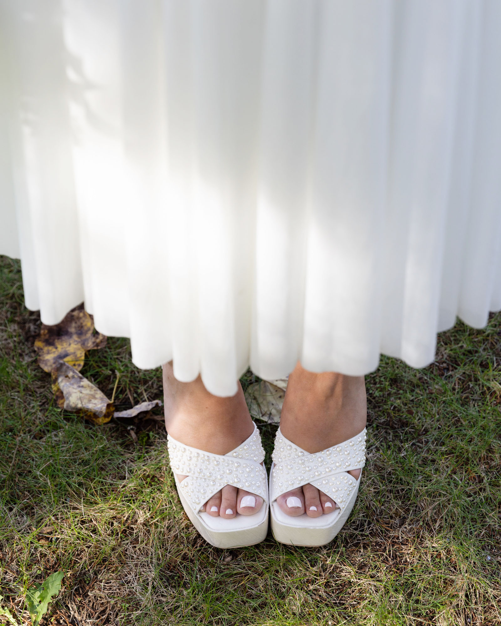 Detail of bride's white, pearl-studded platform sandals at a wedding ceremony at Bowman's Hill Wildflower Preserve in New Hope, PA