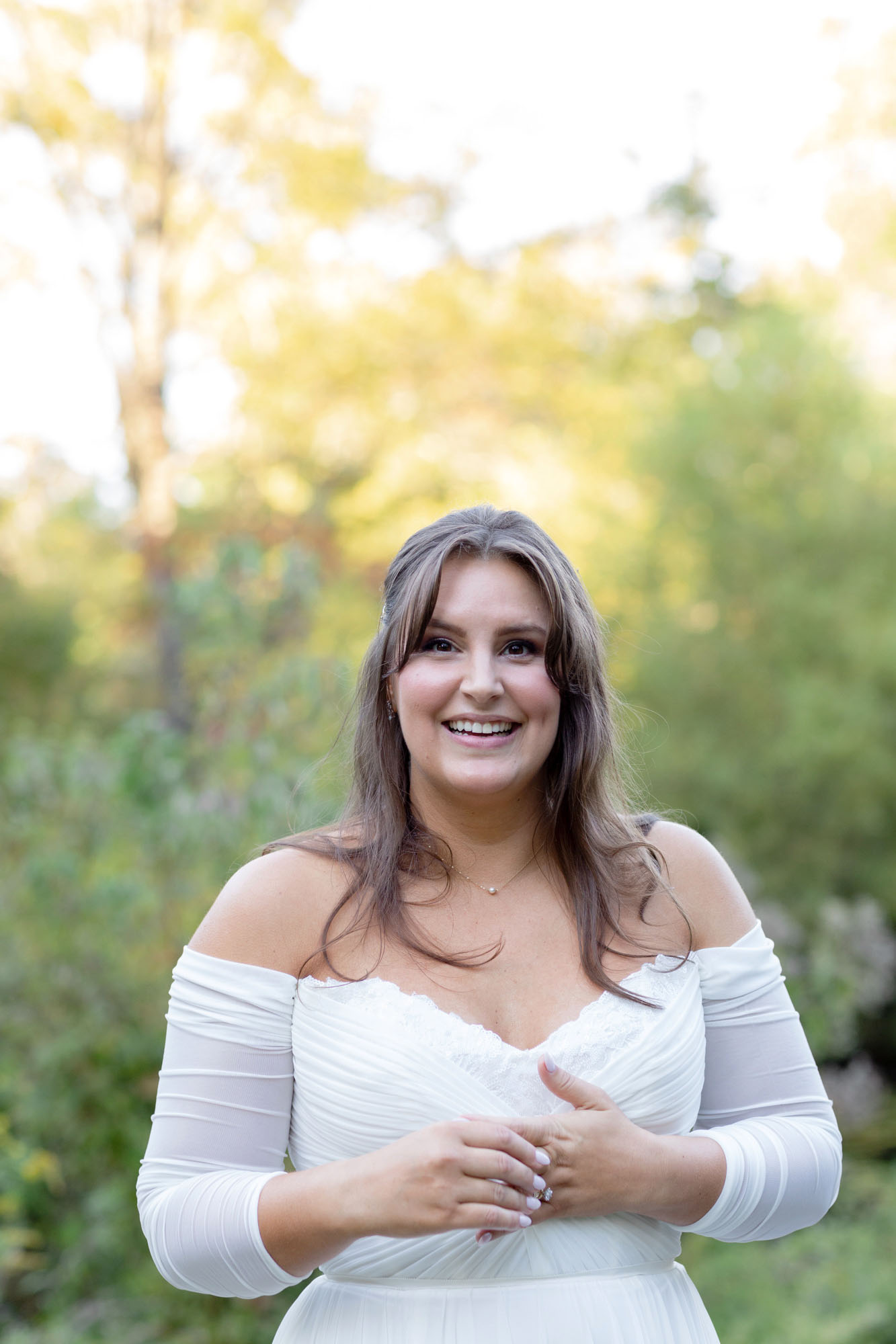 Smiling bride in an off the shoulder chiffon dress before her wedding ceremony at Bowman's Hill Wildflower Preserve in New Hope, PA