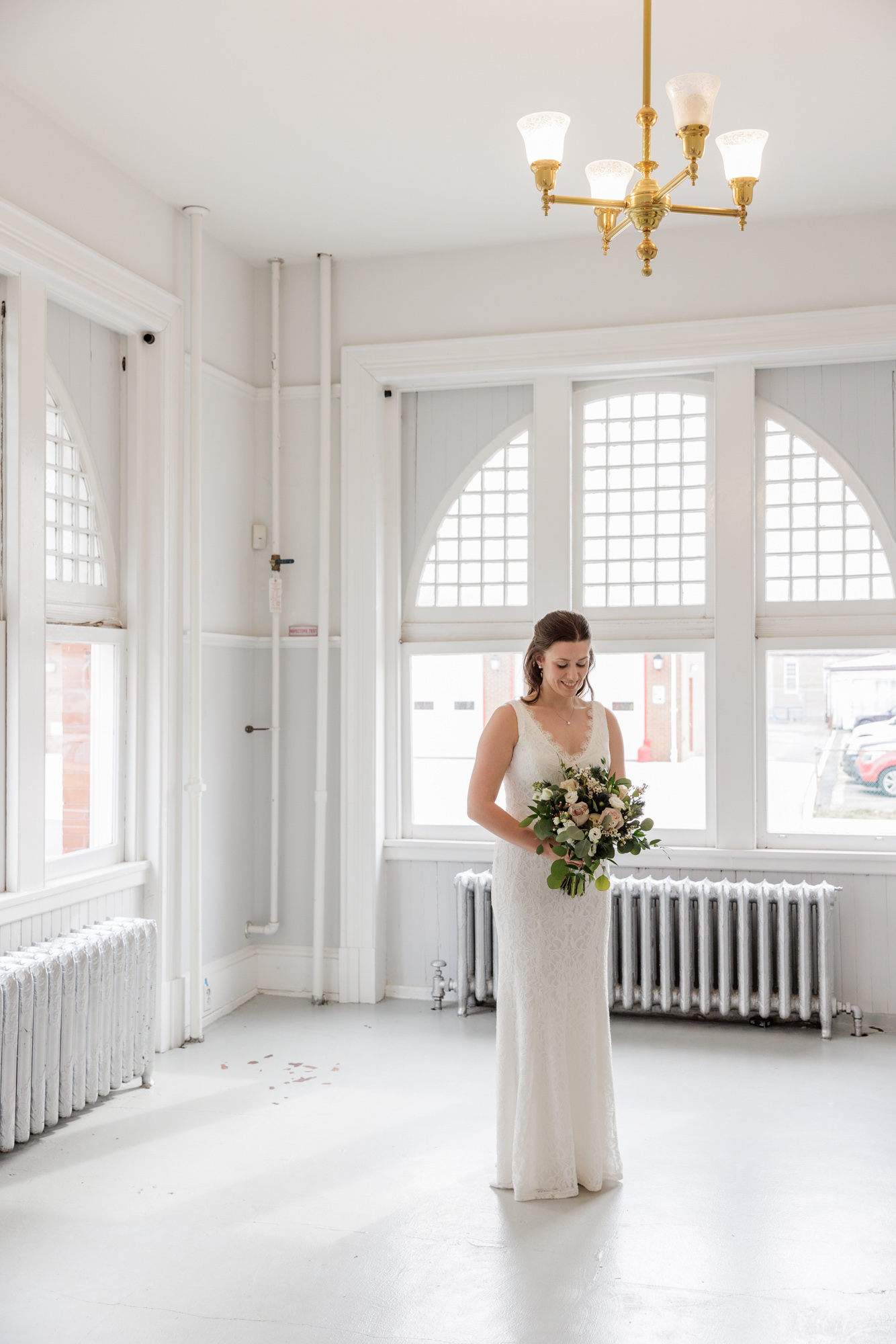 Portrait of an elegant bride looking down at her bouquet before her wedding ceremony inside Old City Hall in Bordentown, NJ 