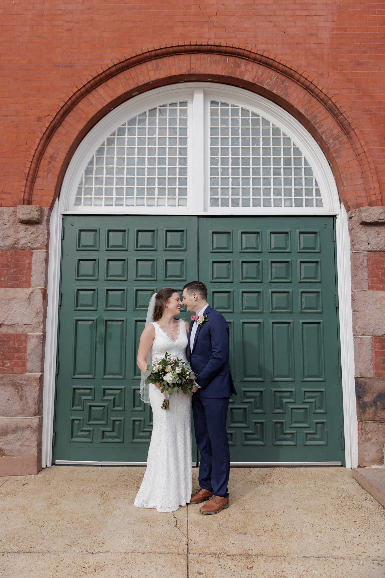 Elegant bride and groom in front of an arched doorway with dark green doors at the historic Old City Hall in Bordentown, NJ