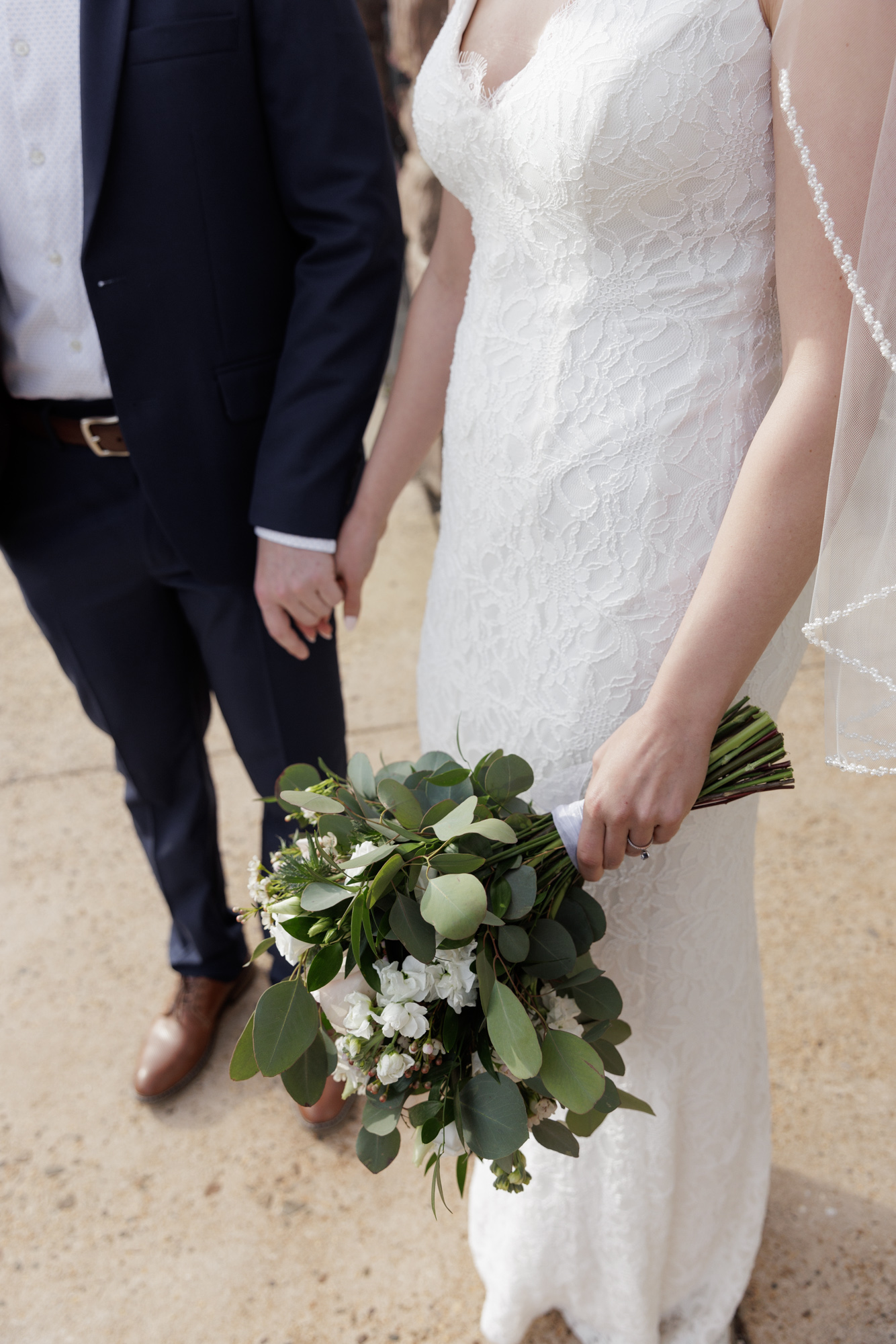 Detail of an elegant bride and groom holding hands and the bride holding a wedding bouquet at a wedding in Bordentown, NJ