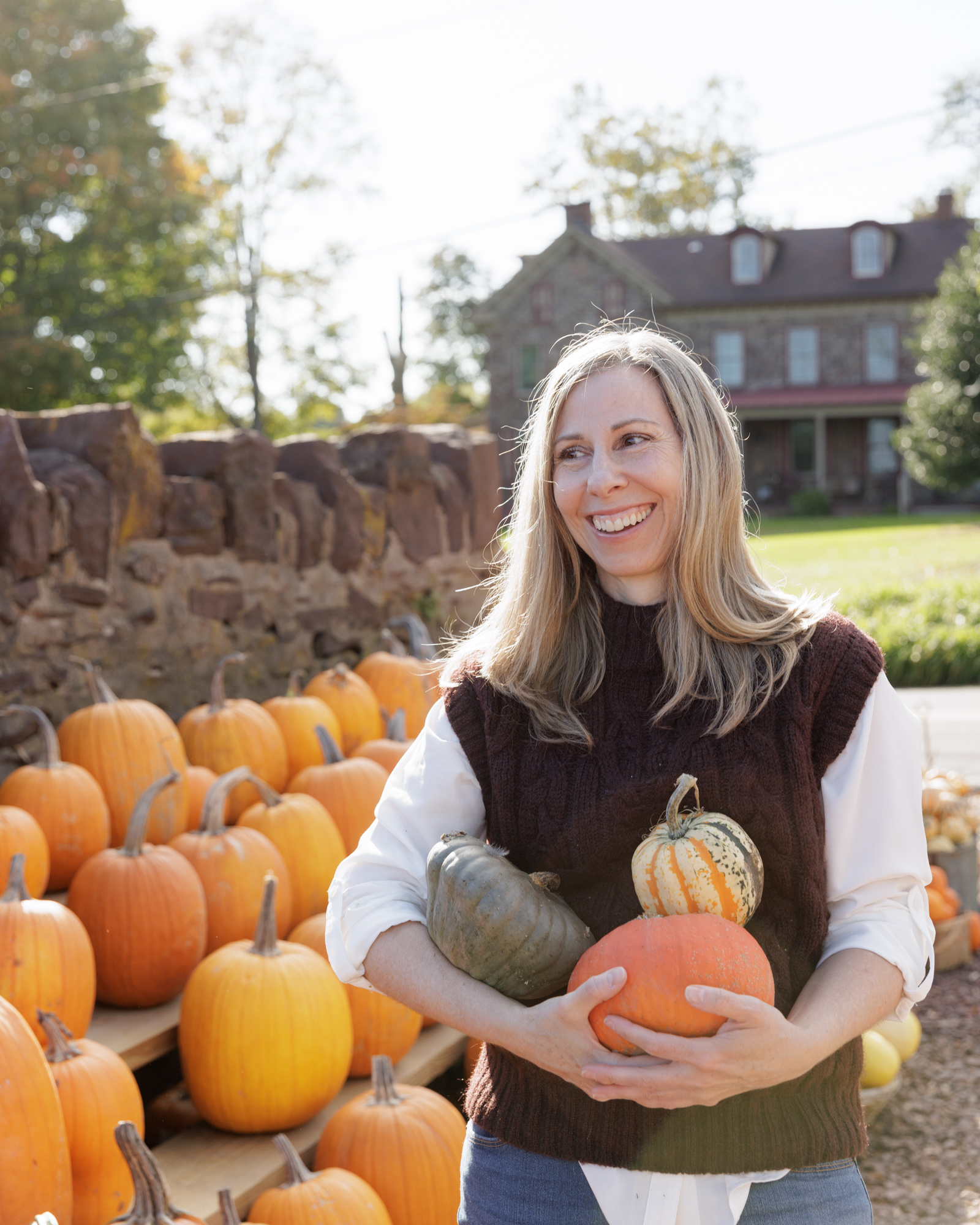 Creating Integrative Health coach, Erin Orekar, cradles pumpkins in her arms at a local farm stand in Bucks County, PA