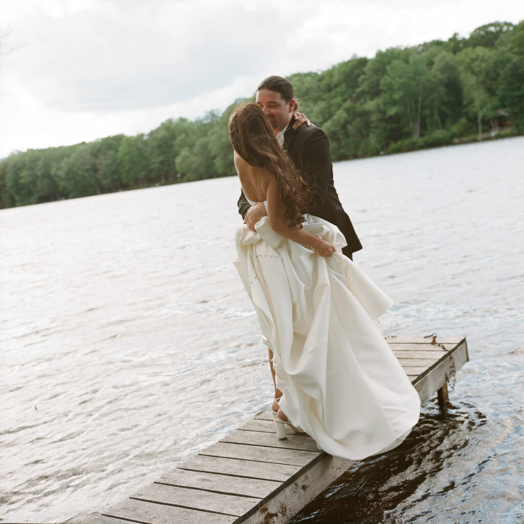 a bride and groom kissing on a dock during golden hour at Mountain Springs Lake Resort in Reeders, PA