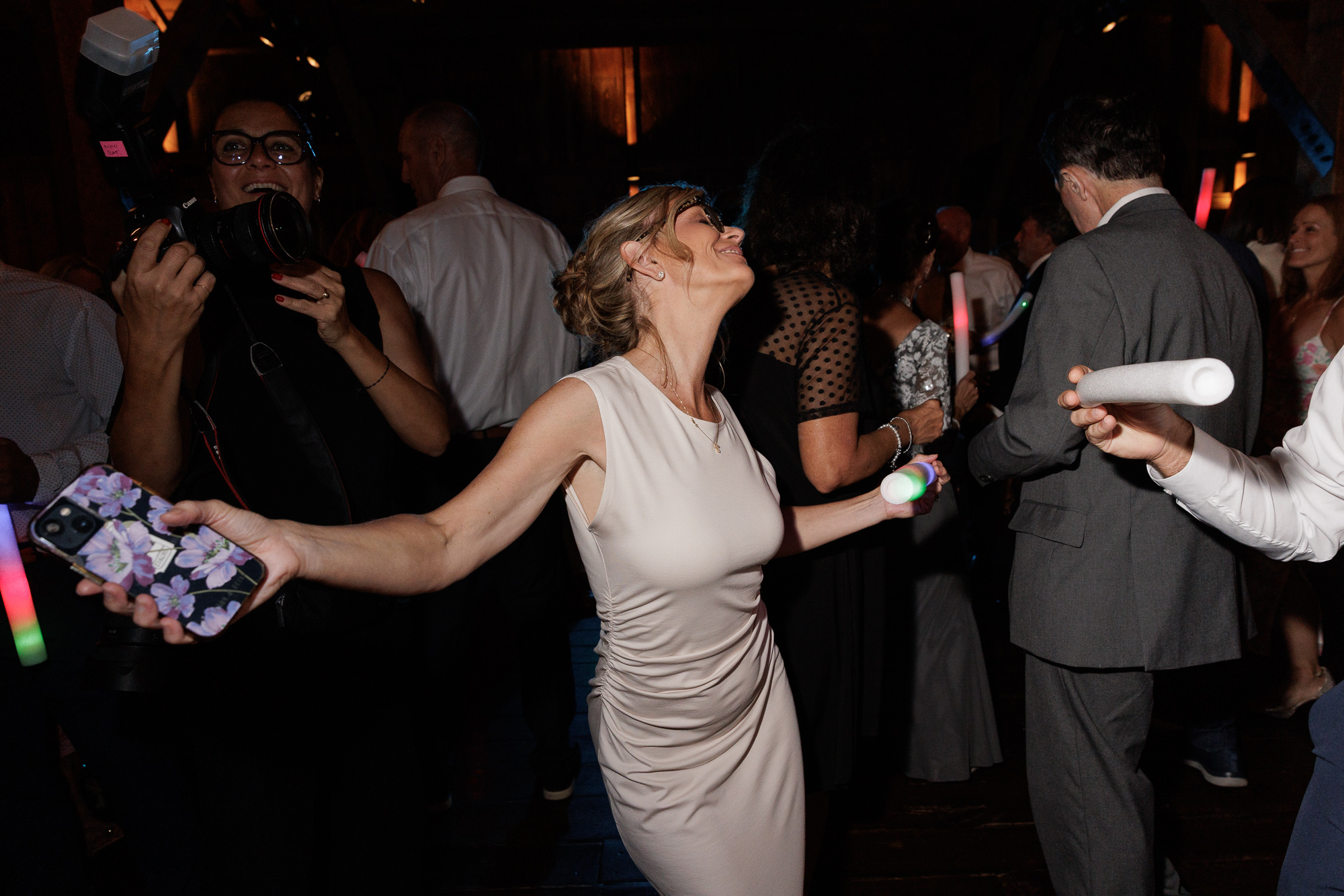 Woman in an elegant champagne colored gown throws her head back and her arms wide open while dancing in the Barn at Farm at Eagles Ridge in Lancaster, PA