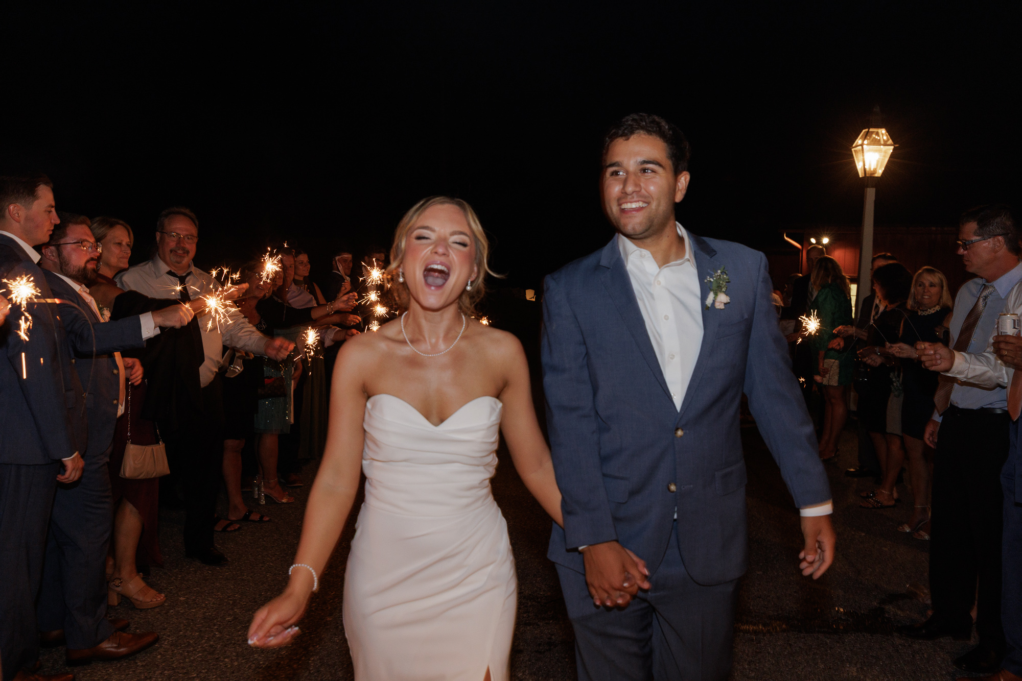 Bride yells in celebration while hand in hand with groom during a sparkler exit at Farm at Eagles Ridge in Lancaster, PA