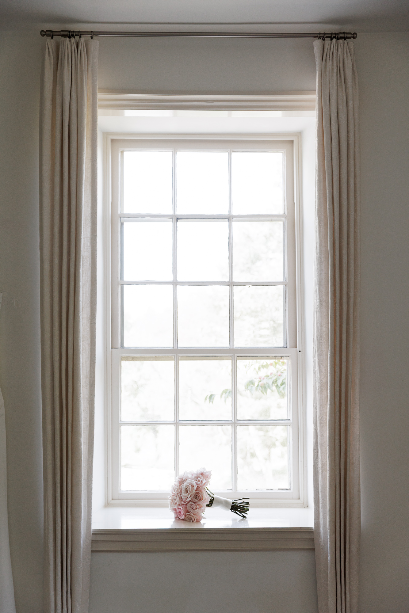 A lush bouquet of soft pink roses rests on a windowsill in the historic house at Farm at Eagles Ridge in Lancaster PA