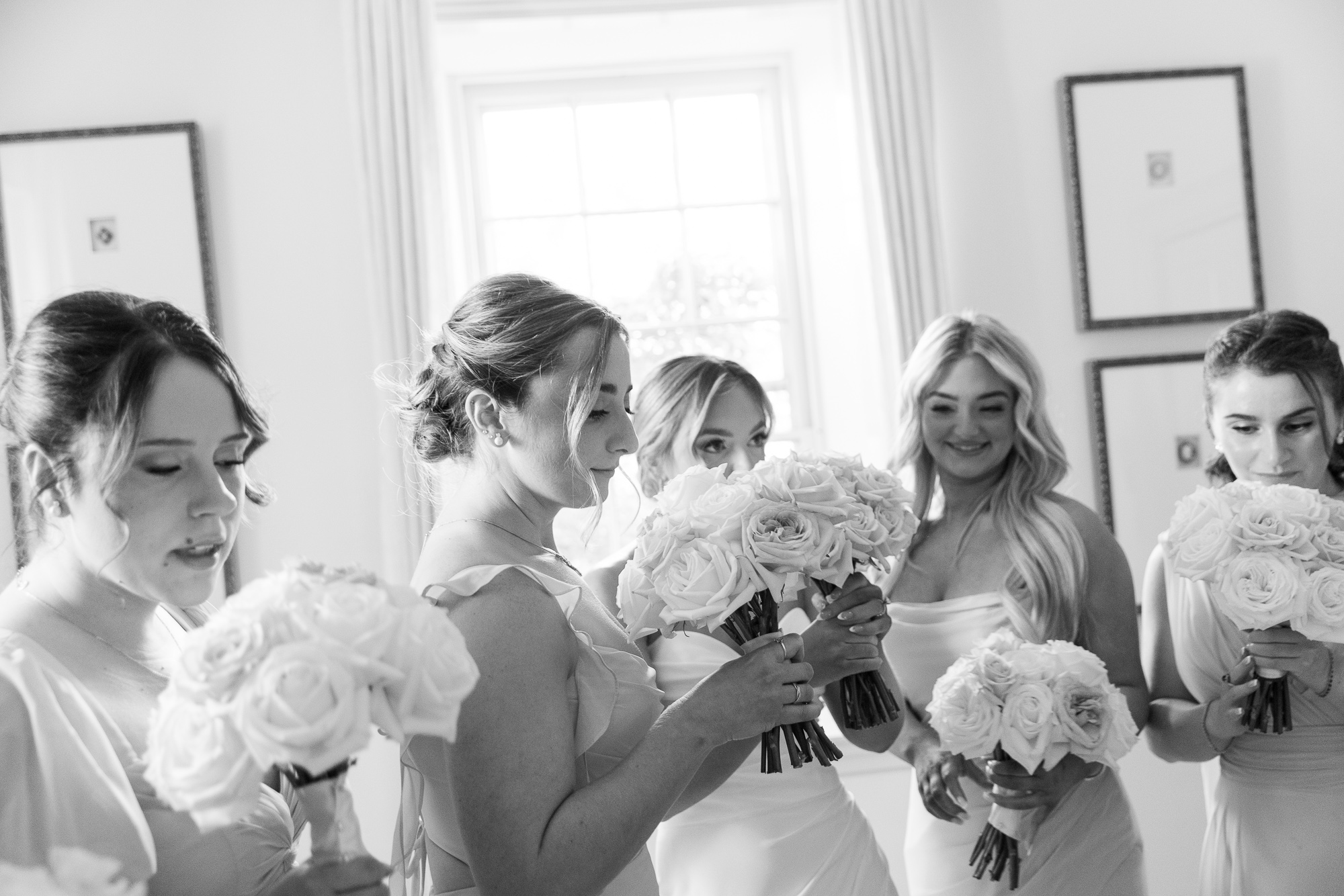 A bride surrounded by bridesmaids enjoy holding their bouquets and taking in the floral scent before a wedding ceremony at Farm at Eagles Ridge in Lancaster, PA
