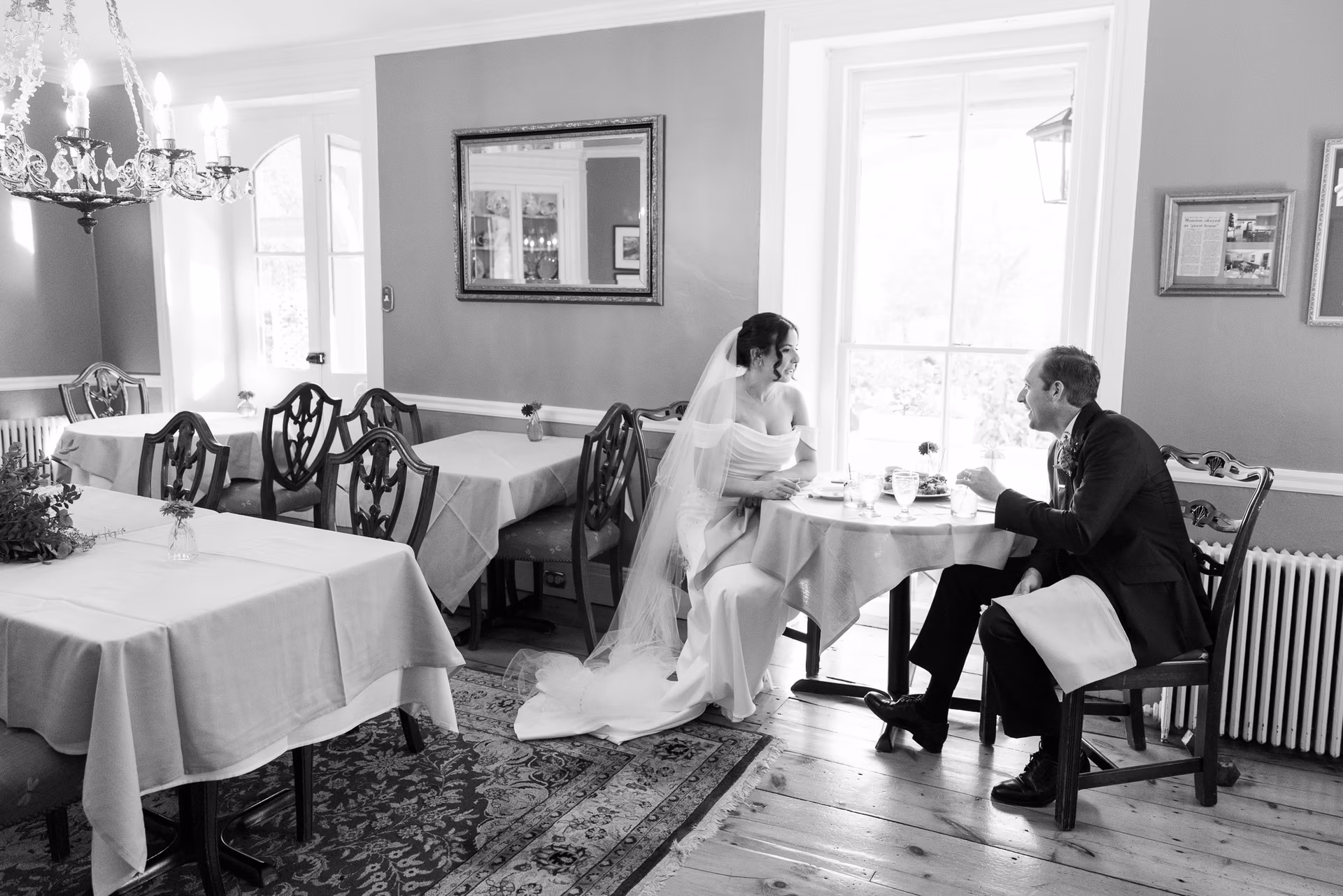 Bride in elegant long gown and veil and groom in dark suit enjoy a moment along with an h'ors d'oeuvre and drink during their cocktail hour in the dining room of the Woolverton Inn