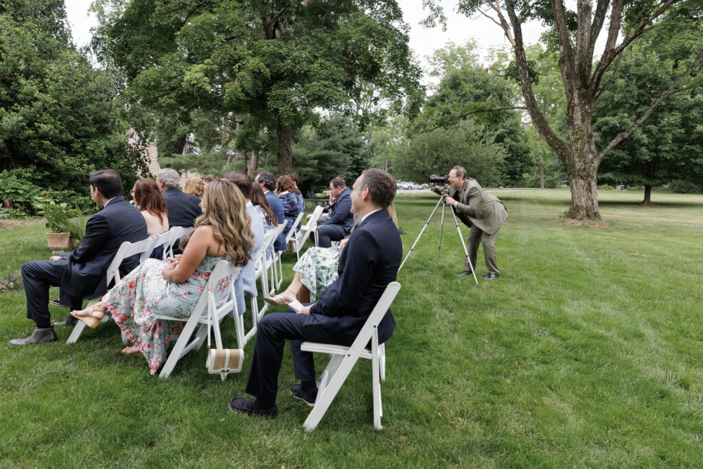 A dad with a camera on a tripod takes a photo during a micro wedding ceremony