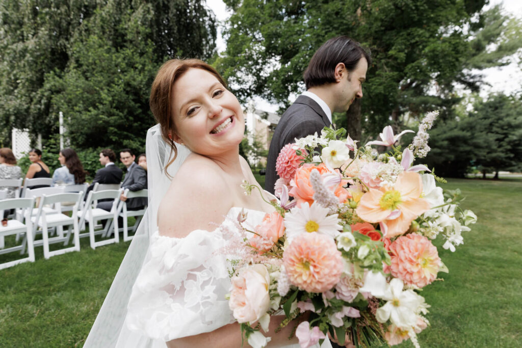 A bride, turns to beam at the camera as she and the groom walk down the aisle after a micro wedding in Stockton, NJ