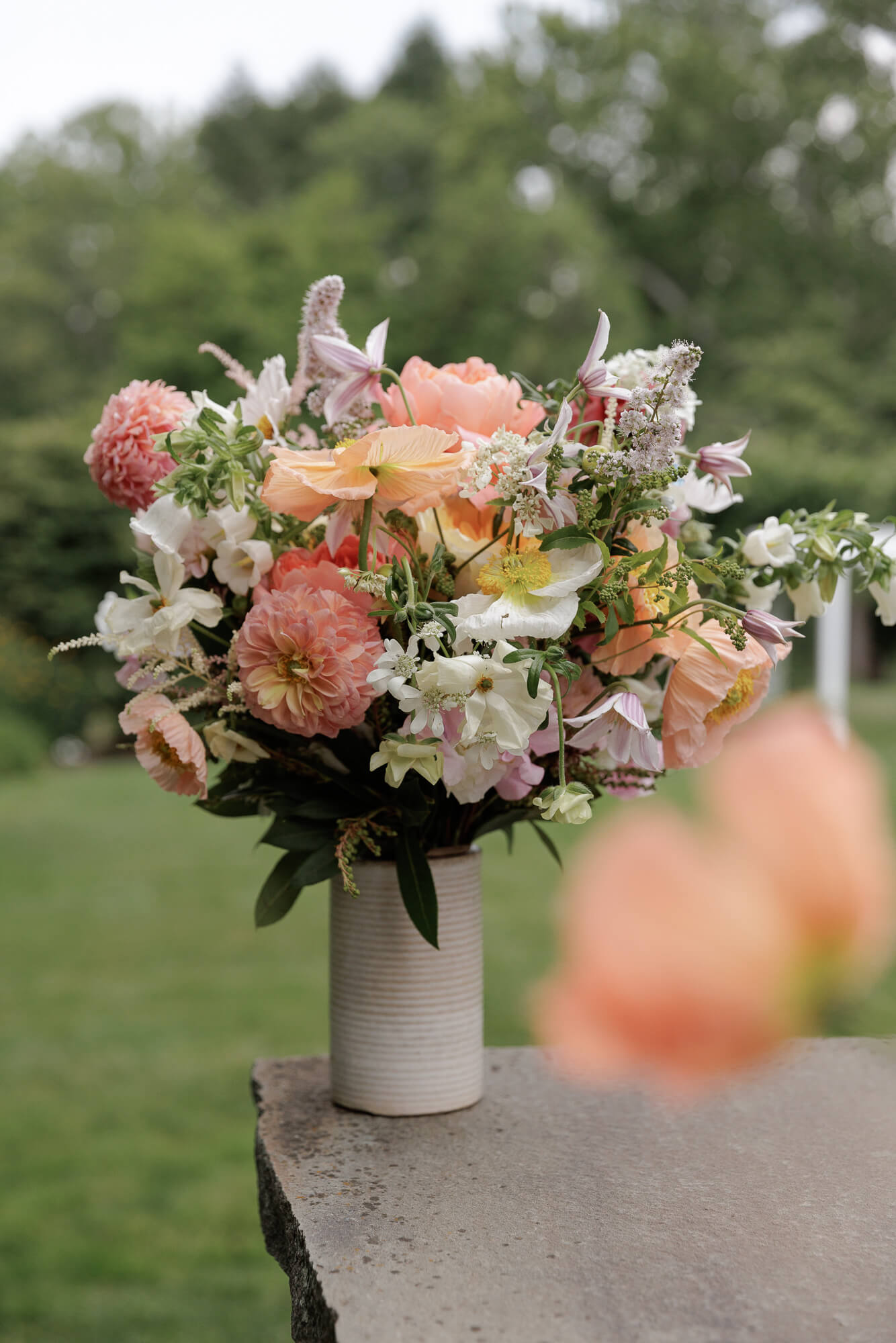 A floral arrangement in a ceramic vase rests on an outdoor flagstone bar