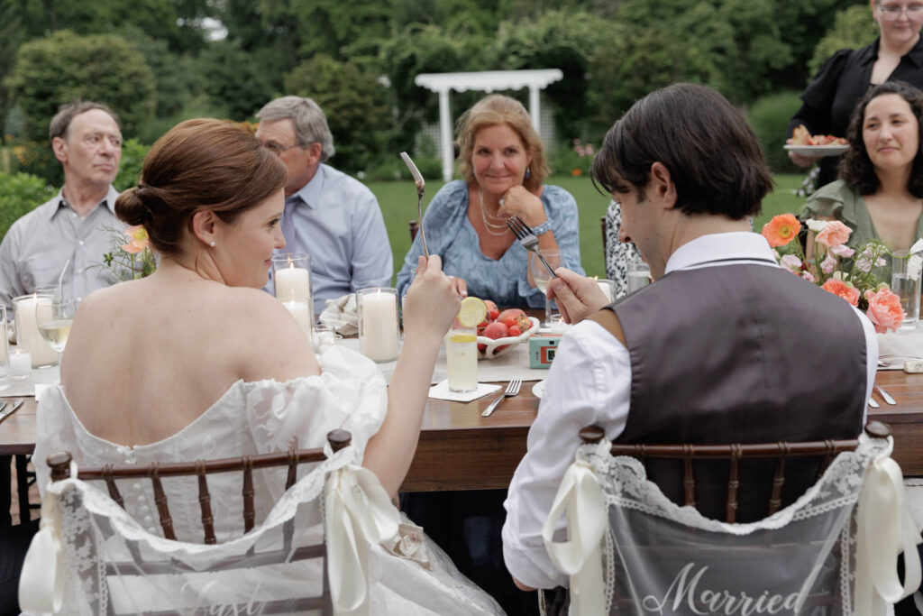Bride and groom clink forks to toast each other during their wedding dinner