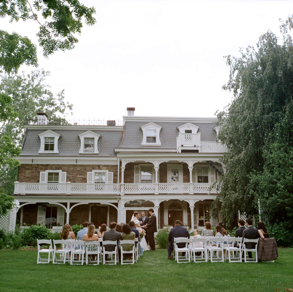 Film photography of a micro wedding ceremony with the Woolverton Inn as a backdrop