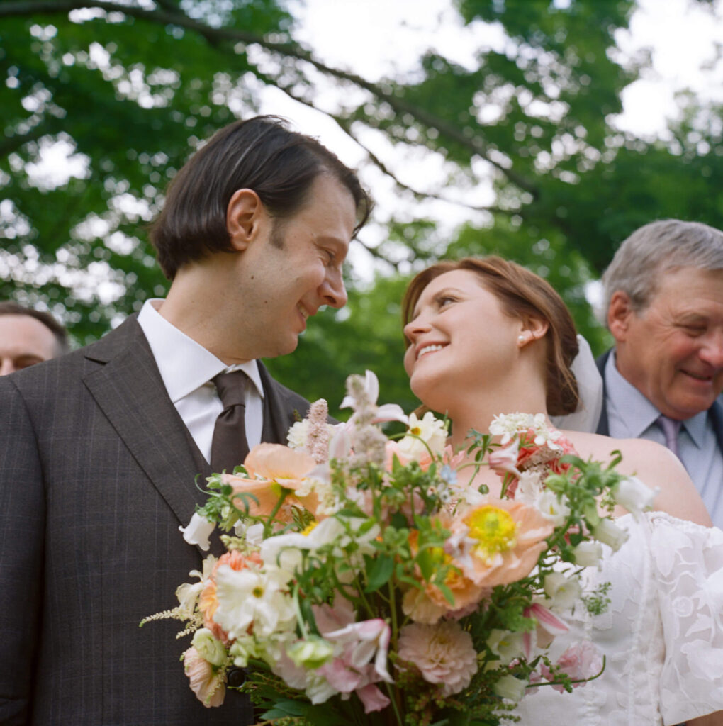 Film photograph of a bride and groom turning to smile at each other during a family portrait