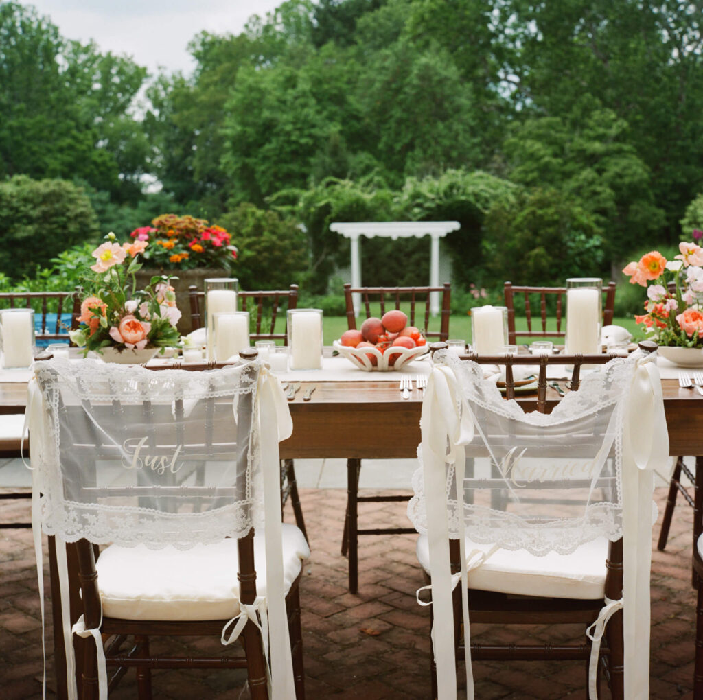 Film photo detail shot of lace panels tied with satin ribbon adorning couple's chairs at an outdoor micro wedding, one on left says "Just" the right says "Married"
