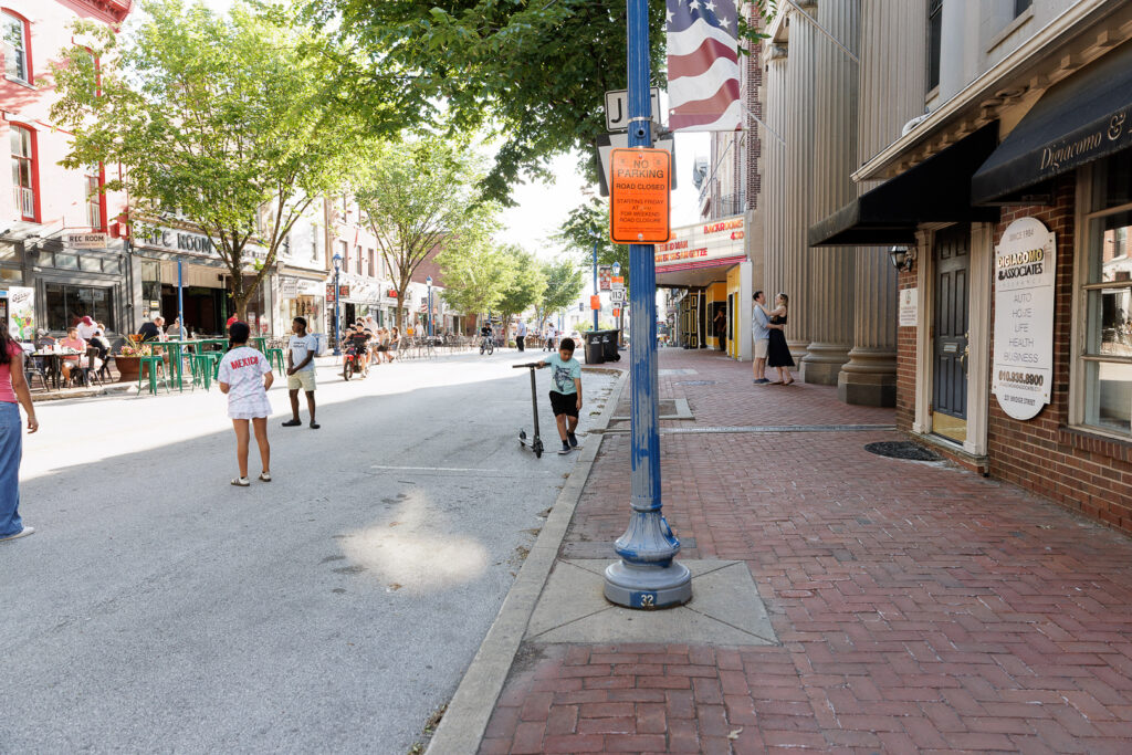 Couple embraces on sidewalk of Bridge Street in Phoenixville where they had their first date, during engagement session photography
