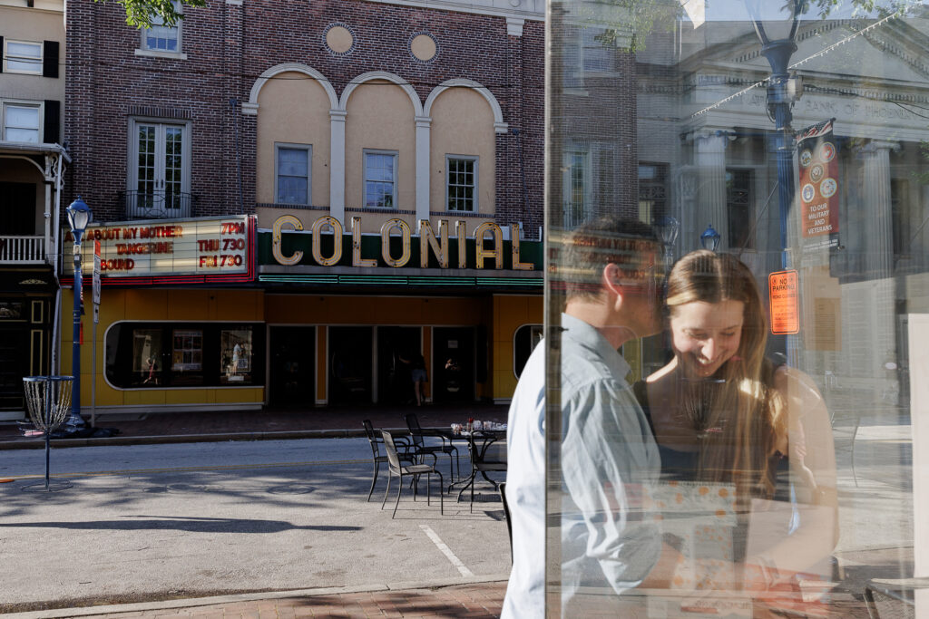 Selah and Brendan look through the window of their favorite bookshop during engagement session photography in Phoenixville
