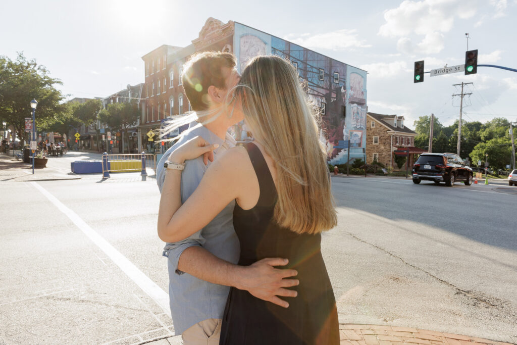 Selah and Brendan embrace on sidewalk of Bridge Street, Phoenixville where they had their first date, during engagement session photography